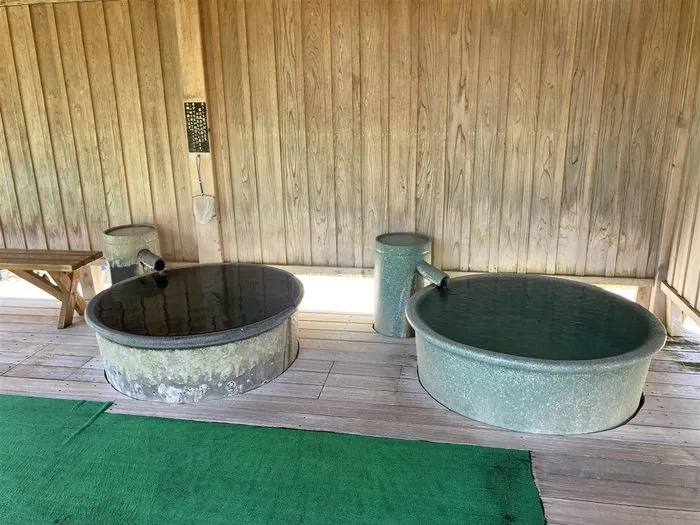 木造あずまやの下に並ぶ金属製の丸桶水風呂