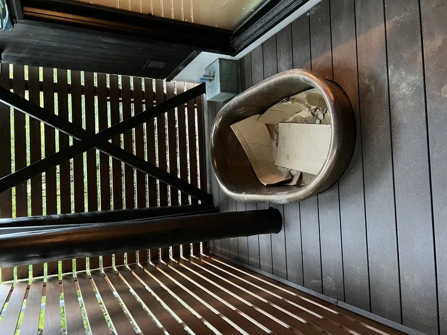 当社施工：黒い外壁のサウナ小屋の前、木のデッキに置かれた水風呂用のバスタブ