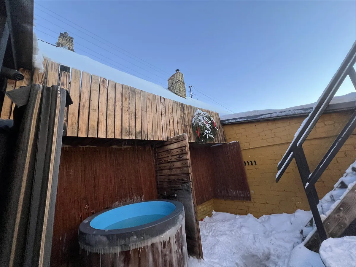 雪の中庭に置かれた、つららの下がる樽型の水風呂