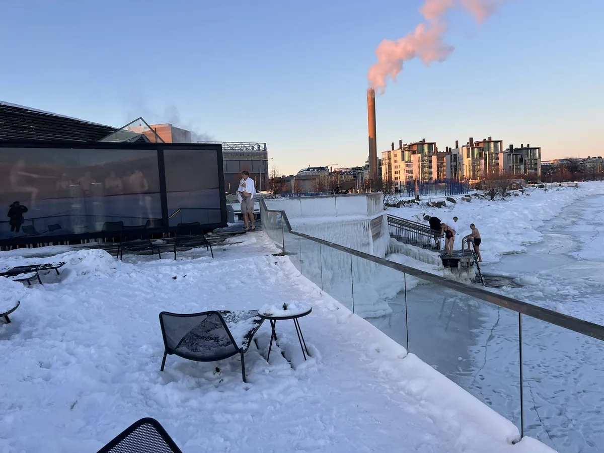 雪のテラスの先に、凍った海へ下りる階段と水着の人