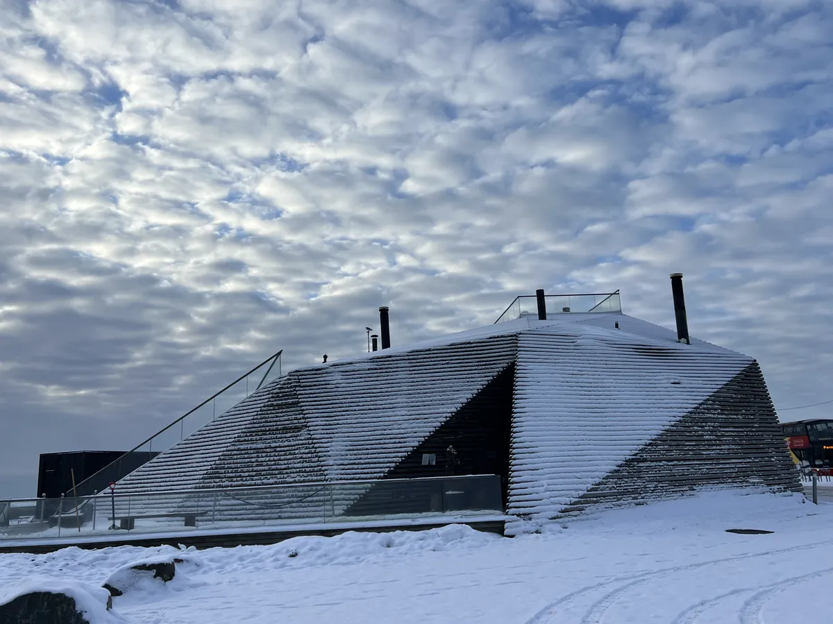 雪の中に建つ、木の板で覆われた角ばったサウナの建物