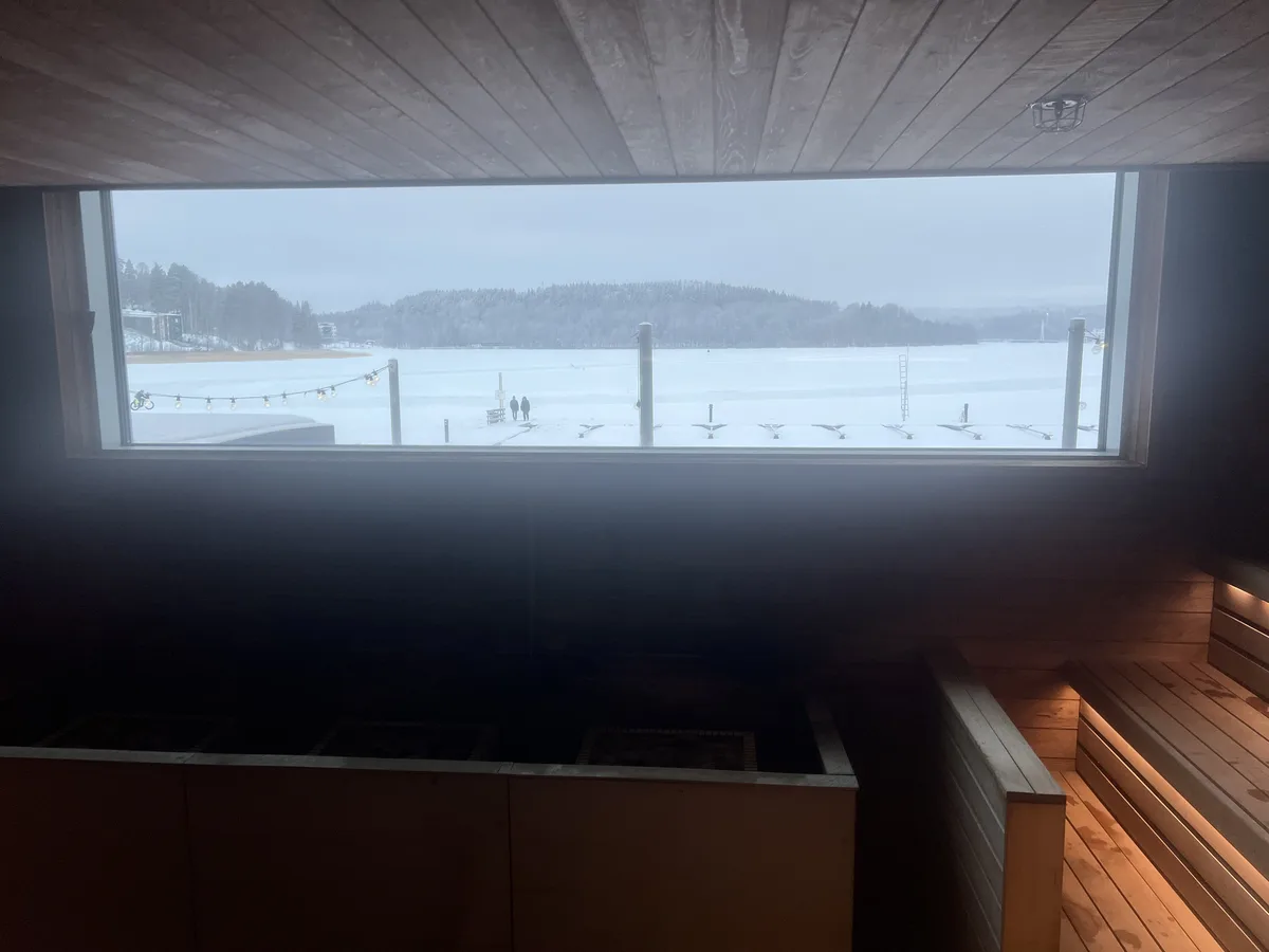 フィンランドのサウナ室内。パノラマ窓の向こうに凍った湖と雪山が広がる